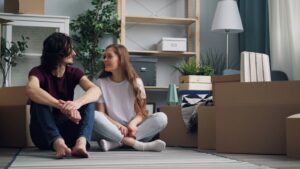 a man and a woman sitting on the floor in front of moving boxes