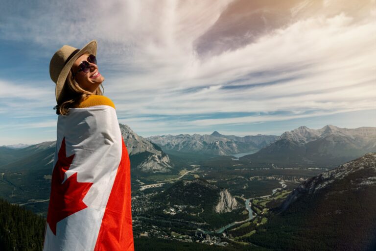 smiling woman wearing brown hat and sunglasses while holding Canada flag